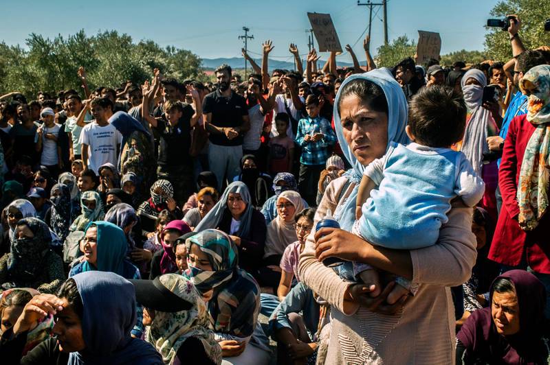 A woman holds a baby as refugees and migrants take part in a demonstration against their living conditions at the Moria camp on the island of Lesbos, on October 1, 2019. - Around a thousand migrants staged a fresh protest on October 1, 2019 in Europe's largest migrant camp on the Greek island of Lesbos, two days after a deadly fire at the vastly overcrowded facility. (Photo by ANGELOS TZORTZINIS / AFP)