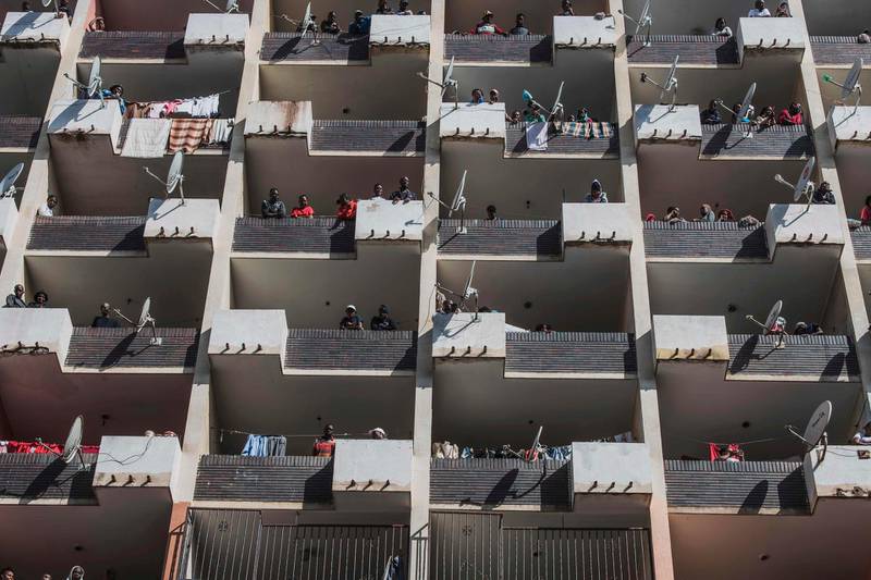 Residents of a Hillbrow, Johannesburg, building observe from the balconies as a police operation is conducted to make sure everyone observes the Country's lockdown.  AFP