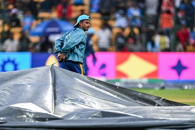 A member of ground staff covers the pitch as rain stops play. AFP