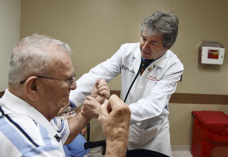 Dr. Michael Miller, right, a professor of cardiovascular medicine, checks the arm strength of Hank Butta, 89, during a consultation at his office at the University of Maryland Medical Center. (Kenneth K. Lam/Baltimore Sun/Tribune News Service via Getty Images)