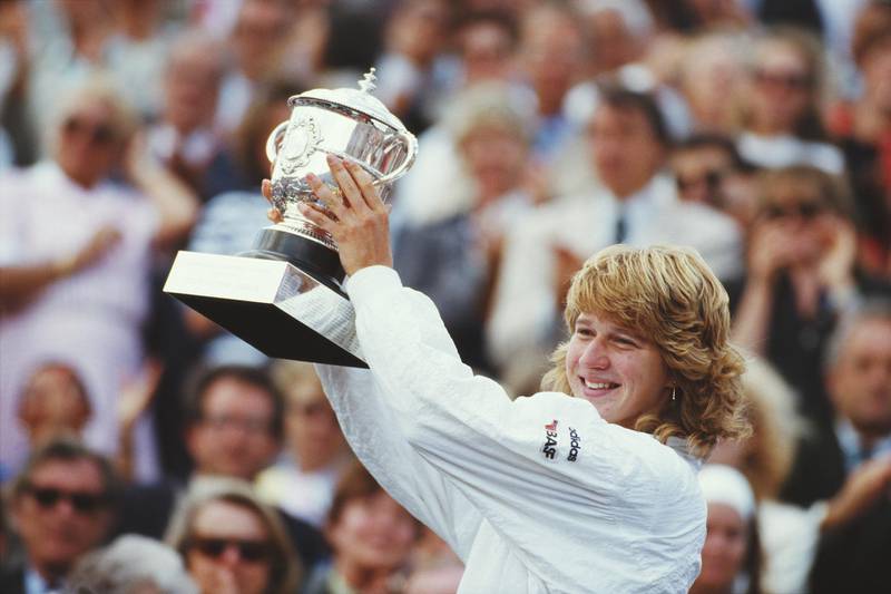 Steffi Graf of Germany celebrates with the trophy after winning her Women's Singles Final match against Martina Navratilova at the French Open Tennis Championship on 6 June 1987 at the Stade Roland Garros Stadium in Paris, France. (Photo by Chris Cole/Getty Images)