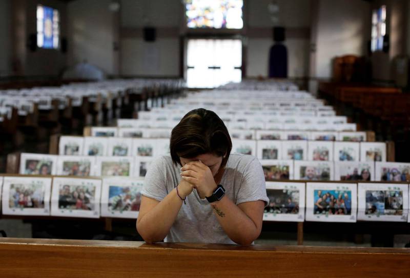 Adriana Brenes prays during a live streamed mass as photos of the congregation are displayed over the church's benches at the Nuestra Senora de Fatima church, San Jose, Costa Rica. Reuters