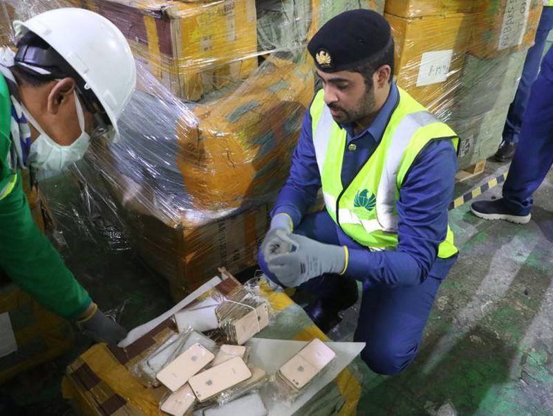 Dubai Customs officers uncover a shipment of fake mobile phones. The customs office often recycles counterfeit goods to protect consumers and limit environmental damage. Courtesy: Dubai Customs