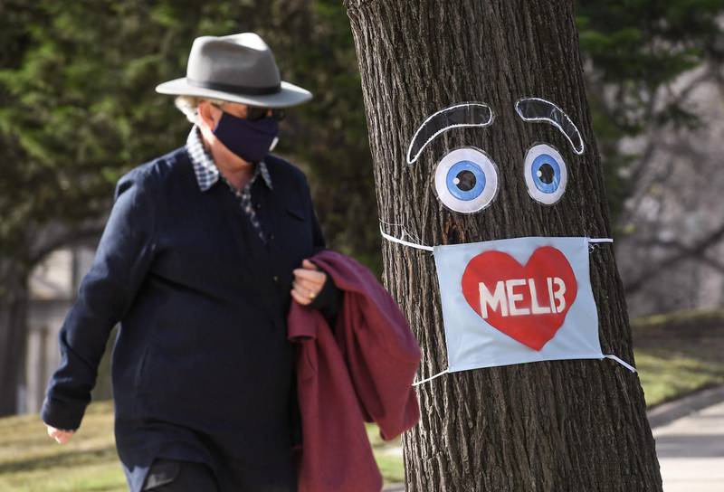 A man walks past a large face mask pinned to a tree in Melbourne after the state announced new restrictions as the city battles fresh outbreaks of the Covid-19 coronavirus in Australia. AFP