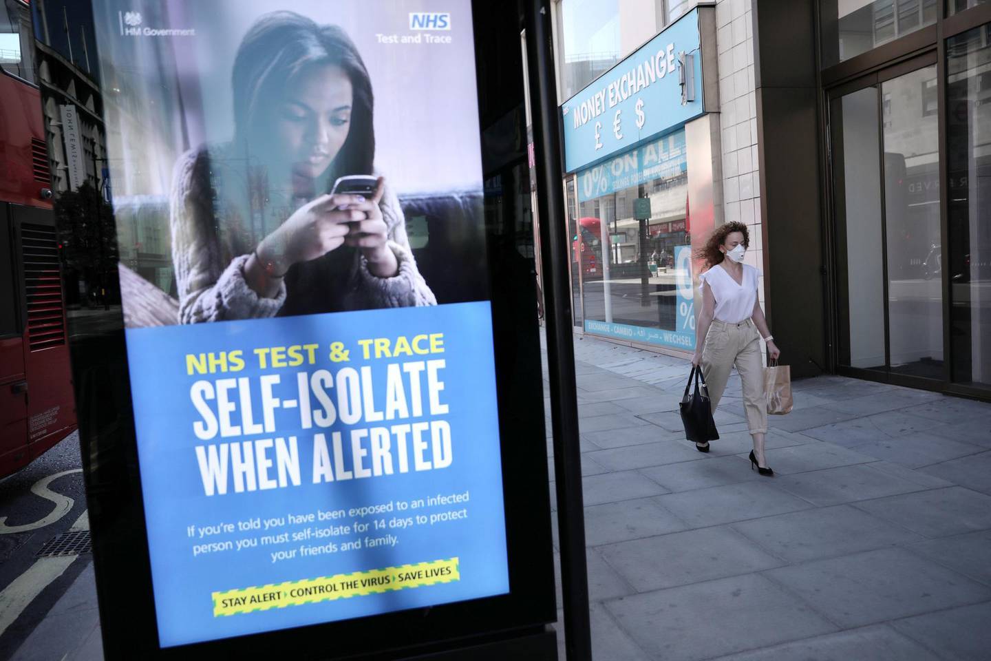 LONDON, ENGLAND - JUNE 15: A woman walks past an NHS Test and Trace advertisement on Oxford Street as stores reopen following closure due to the coronavirus outbreak on June 15, 2020 in London, United Kingdom. The British government have relaxed coronavirus lockdown laws significantly from Monday June 15, allowing zoos, safari parks and non-essential shops to open to visitors. Places of worship will allow individual prayers and protective facemasks become mandatory on London Transport. (Photo by Dan Kitwood/Getty Images)