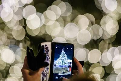 A woman takes a photo with a smartphone of a Christmas tree in front of the Brandenburg Gate in Berlin, Germany. Christmas markets have been cancelled in Berlin this year. EPA
