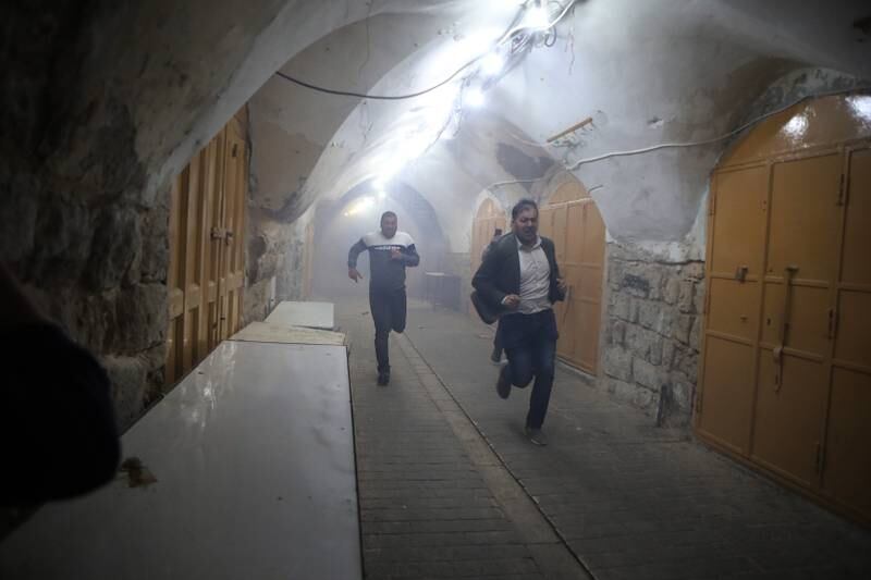 Palestinians run for cover during clashes with the Israeli army in the West Bank city of Hebron, following a protest against Israeli plans to change the status quo in the Ibrahimi Mosque, also known as the Cave of the Patriarchs, to build a lift to serve Jewish worshipers. EPA 