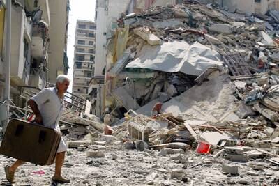 A man passes a destroyed building in the southern suburbs of Beirut, August 10, 2006