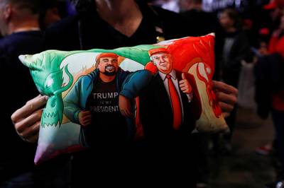 A supporter of U.S. President Donald Trump holds a pillow of him and Kanye West at his campaign rally in Las Vegas, Nevada. Reuters