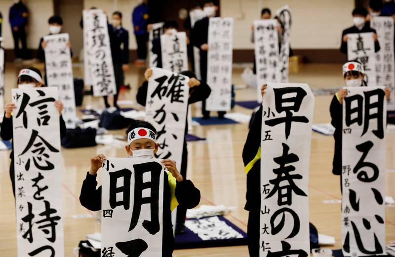 Students in Tokyo wearing masks take part in an annual New Year calligraphy contest. Last year's event was cancelled because of the pandemic. Reuters