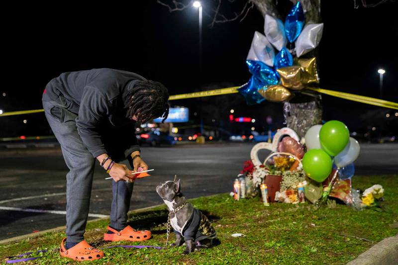Cameron Bertrand with the gun violence activist group Violence Intervention and Prevention talks to his dog at a memorial for those killed.  Getty Images / AFP