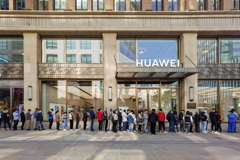 People wearing masks wait in line in front of the Huawei’s flagship store for pre-sales of the Huawei Mate 40 series smartphones, launched in October, in Shanghai. AFP