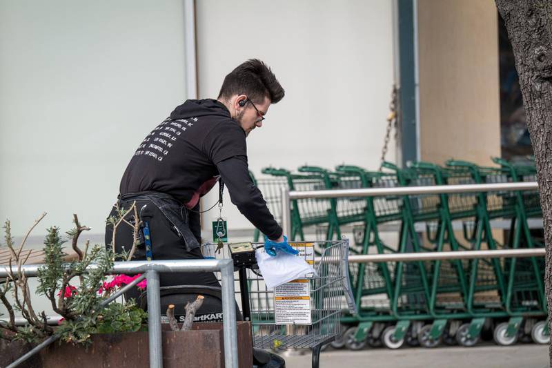 An employee cleans a shopping cart outside a Whole Foods Market Inc. store in Berkeley, California, U.S., on Tuesday, March 31, 2020. Some workers at Whole Foods Market stores across the U.S. called in sick on Tuesday, part of a coordinated action to demand more sick pay and protections for grocery store employees working through the coronavirus pandemic. Photographer: David Paul Morris/Bloomberg
