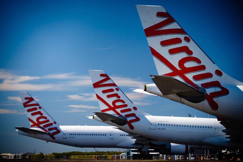 Virgin Australia aircraft are seen parked on the tarmac at Brisbane International airport on April 21, 2020. Cash-strapped Virgin Australia collapsed on April 21, making it the largest carrier yet to buckle under the strain of the coronavirus pandemic, which has ravaged the global airline industry. / AFP / AFP  / Patrick HAMILTON
