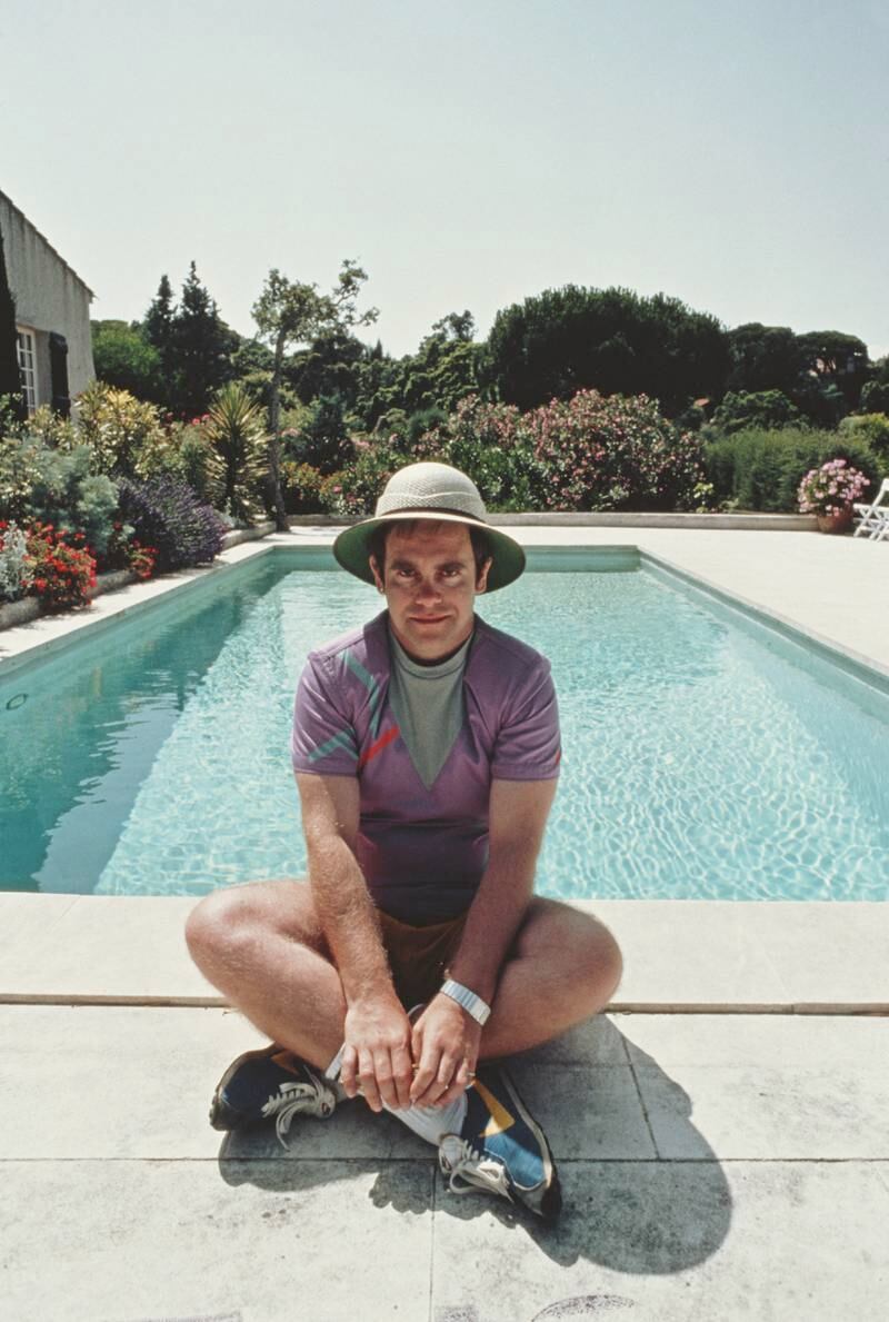 Elton John, in a purple sports kit and a safari-style hat, poses by the pool at his villa in Saint-Tropez in the south of France in January 1982. Getty Images