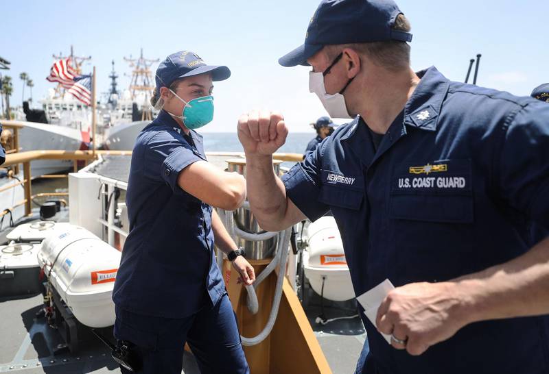 US Coast Guard Lieutenant Caroline Miller elbow bumps Commander Marshall Newberry aboard a patrol boat following monitoring of oil tankers anchored near the ports of Long Beach and Los Angeles amid the coronavirus pandemic off the coast of Long Beach, California. AFP