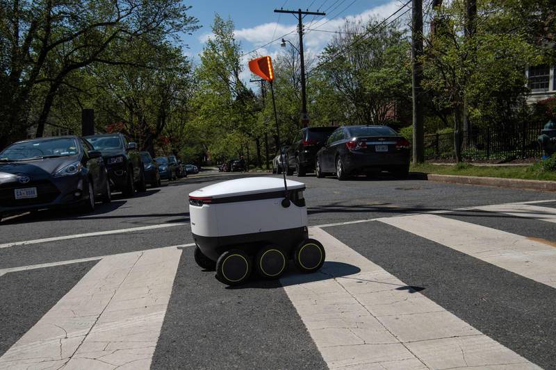 A food delivery robot from the Broad Branch Market grocery store crosses a street in the Chevy Chase neighborhood of Washington, DC, on April 9, 2020 on its way for a delivery. - The store began using the robots about two weeks ago and makes 10-15 deliveries a day within a limited area of the neighborhood. (Photo by NICHOLAS KAMM / AFP)