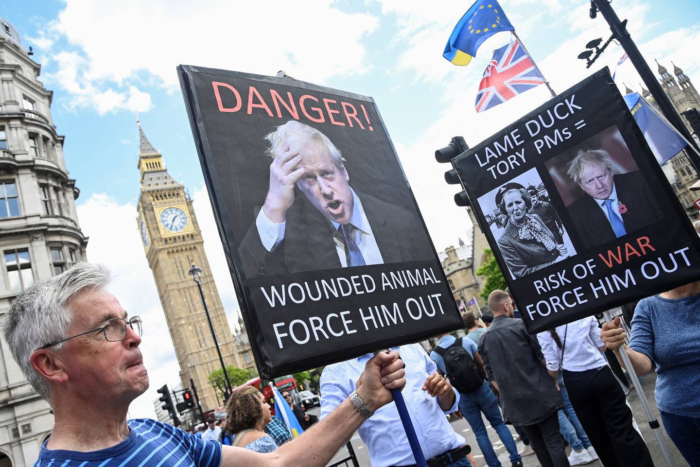 Protestors hold placards depicting British Prime Minister Boris Johnson outside of the houses of Parliament in London. Reuters