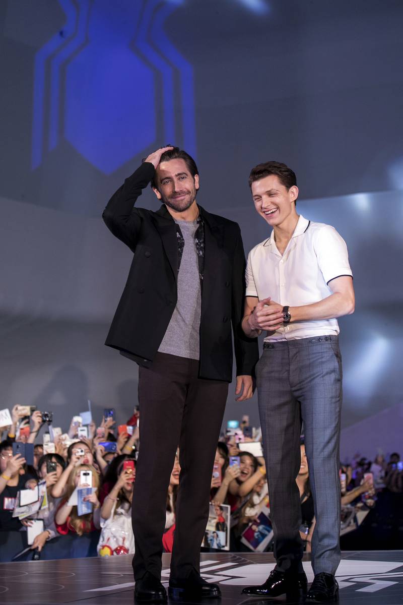 Jake Gyllenhaal and Tom Holland, in a white bowling shirt and grey trousers, attend a 'Spider-Man: Far From Home' fan event in Seoul on June 30, 2019. Getty Images