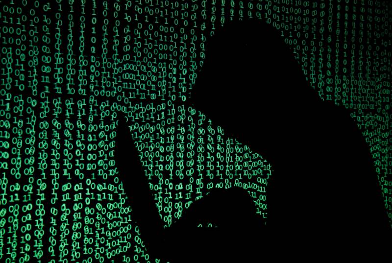 FILE PHOTO: A hooded man holds a laptop computer as cyber code is projected on him in this illustration picture taken on May 13, 2017. REUTERS/Kacper Pempel/Illustration/File Photo