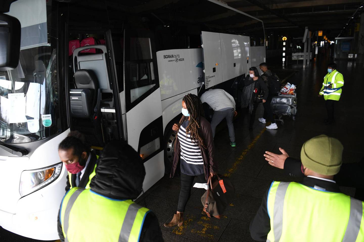Passengers are escorted to a coach at Heathrow Airport to be driven to a mandatory hotel quarantine in west London on February 15, 2021. The policy beginning today will require all UK citizens and permanent residents returning from 33 countries on its so-called travel ban list to self-isolate in a government approved facility for 10 days. 


 / AFP / DANIEL LEAL-OLIVAS

