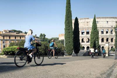ROME, ITALY - JULY 31: Tourists on a bike tour cycle past the Colosseum on July 31, 2020 in Rome, Italy. The Italian government  is to offer a 70-per-cent subsidy, capped at 500 euros, for people who buy a new bicycle. Several European countries are exploring how their work force in post-COVID-19 commute can be environmentally sound, healthy and sustainable. Governments in Europe are fuelling the bicycle trend by offering buying incentives to customers. (Photo by Diana Bagnoli/Getty Images)