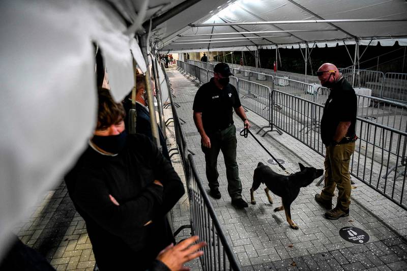 A K-9 handler walks with a specially trained dog that detects coronavirus in people at the American Airlines Arena prior to the NBA basketball match between Miami Heat and the LA Clippers in Miami.   AFP