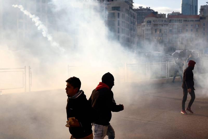 Anti-government protesters run away from tear gas canisters fired by riot police in Beirut. AP Photo