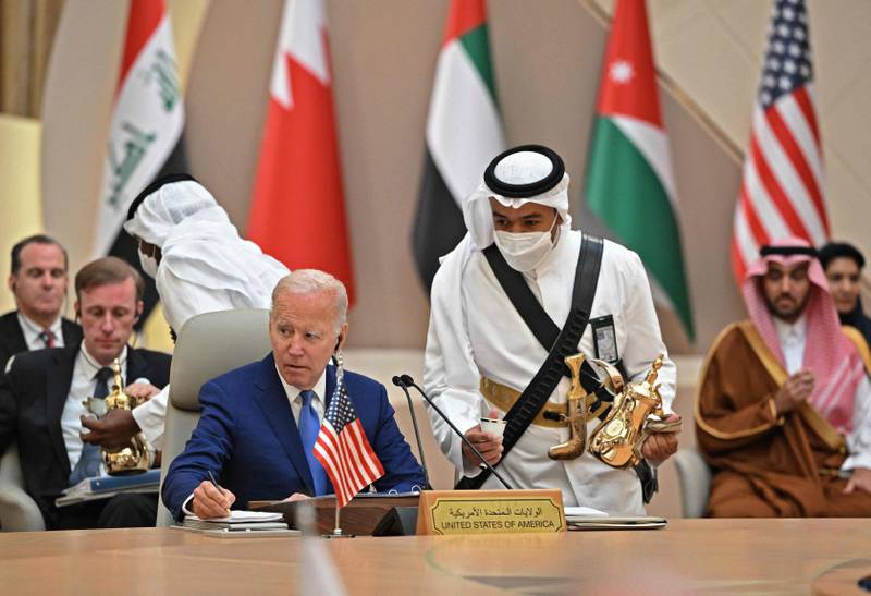 Mr Biden takes notes while an usher serves coffee during the Jeddah Security and Development Summit. AFP