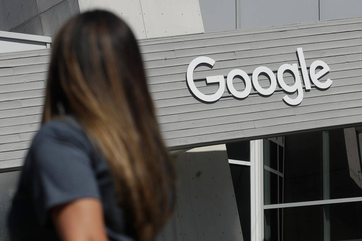 FILE - In this Sept. 24, 2019, file photo a woman walks below a Google sign on the campus in Mountain View, Calif. In the years since Barack Obama and Joe Biden left the White House, the tech industry's political fortunes have flipped. Facebook, Google, Amazon and Apple have come under scrutiny from Congress, federal regulators, state attorneys general and European authorities. (AP Photo/Jeff Chiu, File)