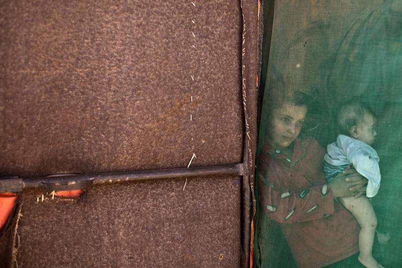 A Syrian refugee girl holds her younger brother while standing at the doorway of her family’s tent at an informal tented settlement near the Syrian border on the outskirts of Mafraq, Jordan. Muhammed Muheisen / AP photo