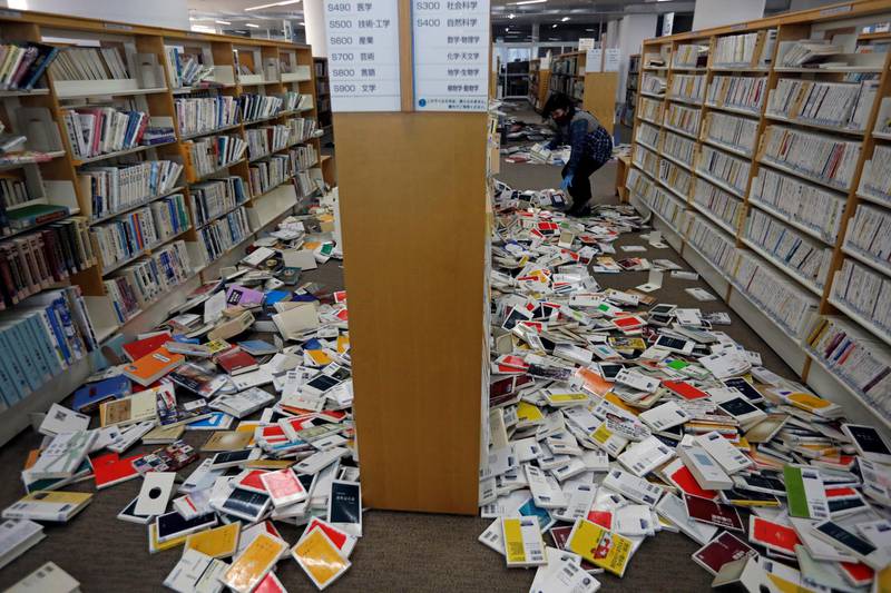 A staff member of library tries to restore books after they fell from book shelves by a strong earthquake at Iwaki City library in Iwaki, Fukushima prefecture, Japan. Reuters
