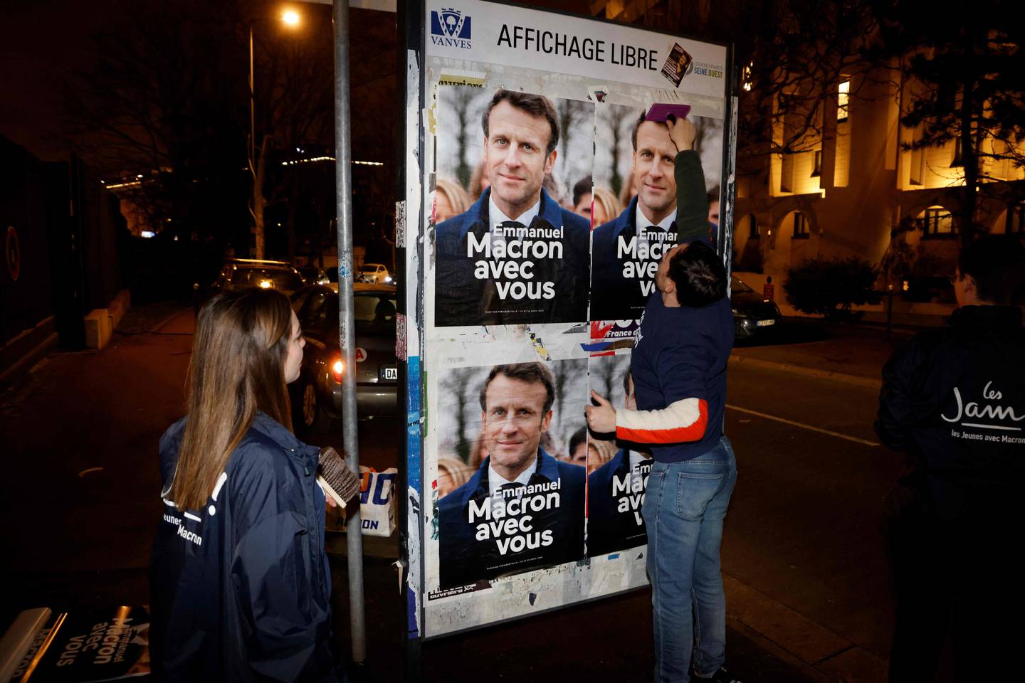 Supporters of French President Emmanuel Macron stick his campaign posters in Vanves, outside Paris, on Wednesday. AFP