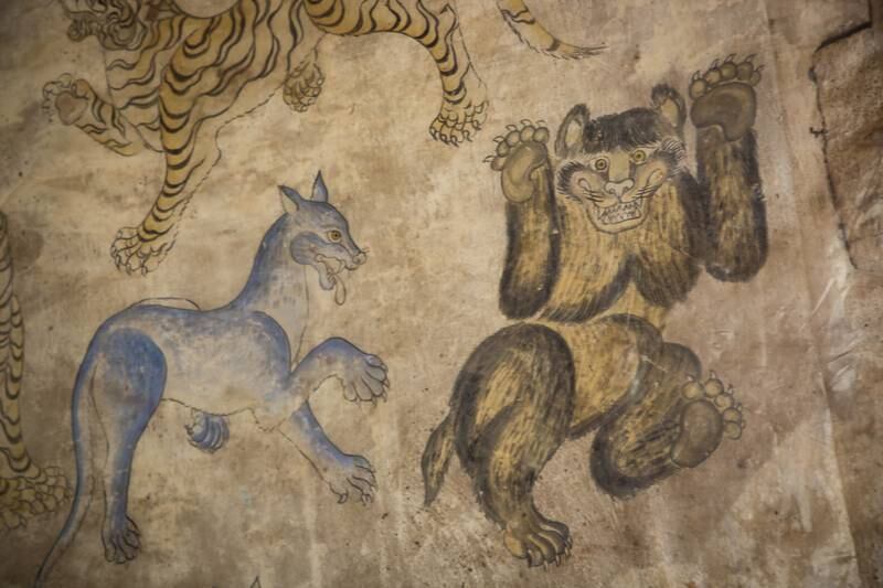 A monastery mural in Bhutan of a yeti being chased by a snow lion 