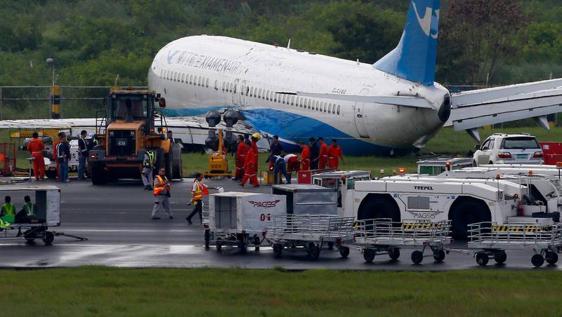 Xiamen Air, a Boeing passenger plane from China, sits on the grassy portion of the runway of the Ninoy Aquino International Airport after it skidded off the runway while landing Friday, Aug. 17, 2018 in suburban Pasay city southeast of Manila, Philippines. All the passengers and crew of Xiamen Air Flight 8667 were safe and were taken to an airport terminal, where they were given blankets and food before being taken to a hotel. (AP Photo/Bullit Marquez)