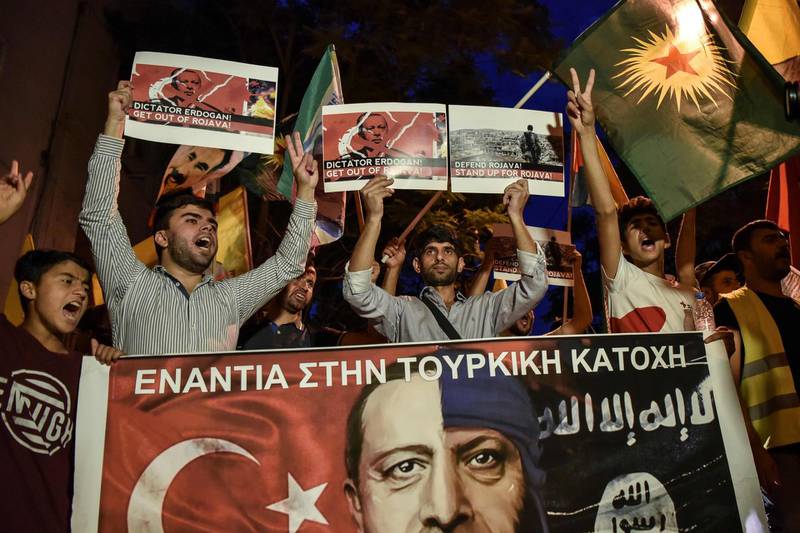 Kurds living in Athens hold flags and banners reading 'Against the Turkish occupation' as they protest near the Turkish embassy in Athens. AFP