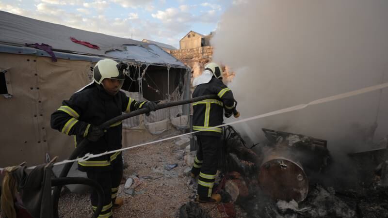 Firefighters work at Maram camp after it was hit by rockets. EPA