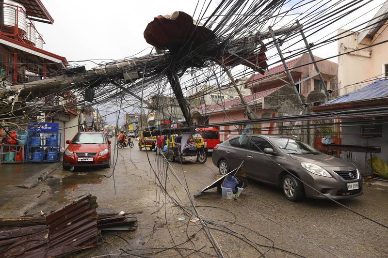 Cars pass a toppled electricity post in Surigao city. AP
