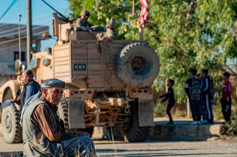 A Syrian elderly man sits near a US armoured vehicle on patrol in the village of Ein Diwar in Syria's northeastern Hasakeh province. AFP