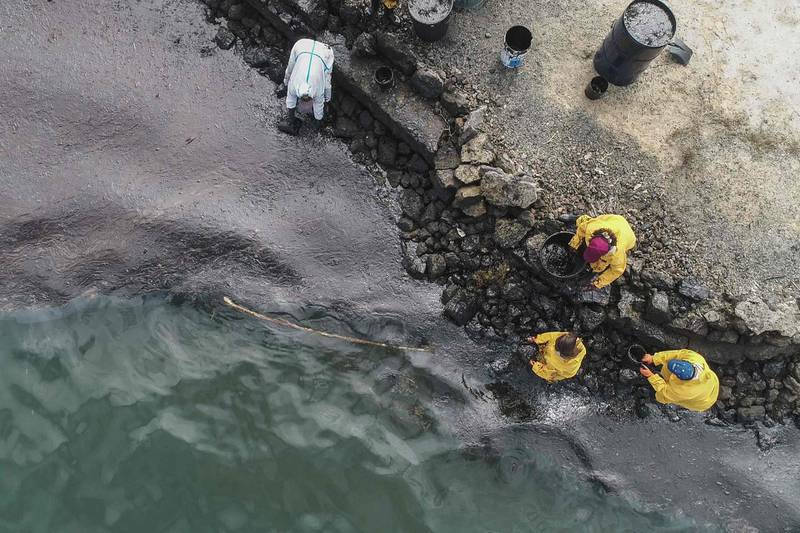 An aerial view shows people scooping leaked oil.  AFP