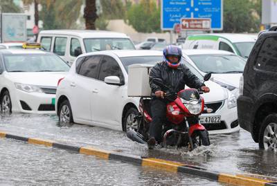 A delivery man on his motorcycle braves the flood. Victor Besa for The National