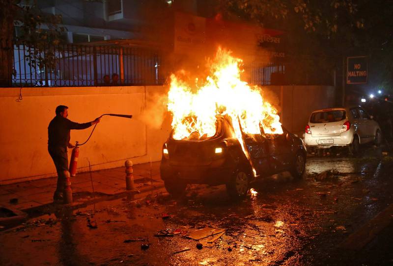 A man tries to extinguish a burning car after demonstrators set it on fire during a protest against a new citizenship law, in New Delhi, India, December 20, 2019. REUTERS/Stringer