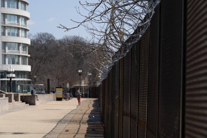 A woman jogs next to a barbed wire security fence near the US Capitol building. Willy Lowry / The National