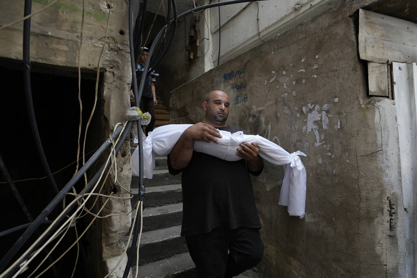 FILE - A man carries the body of a young girl from the family house before the funeral procession for seven people killed when a boat packed with migrants sunk over the weekend as the Lebanese navy tried to force it back to shore, in Tripoli, north Lebanon, on April 25. AP