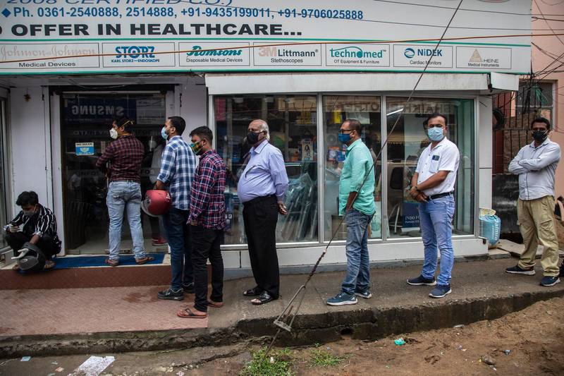 Masked customers line up outside a pharmacy to buy medicines in Guwahati. AP