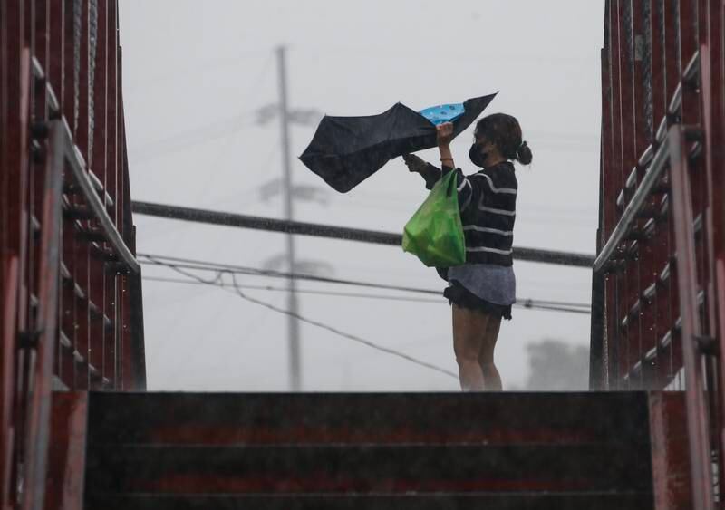 A woman struggles to hold her umbrella amid gusts of wind in Quezon City, Metro Manila. EPA