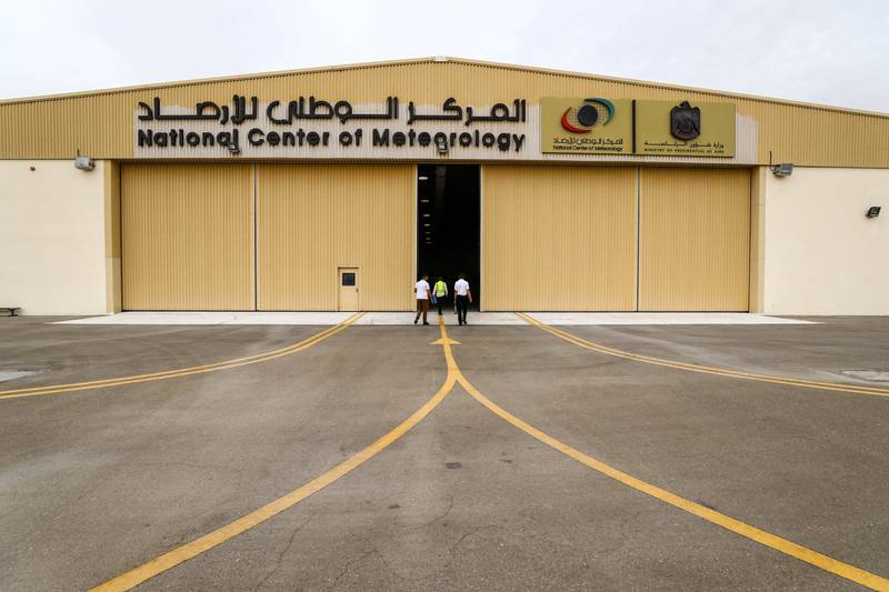 Employees walk towards a hangar at Al Ain International Airport after a cloud-seeding flight.