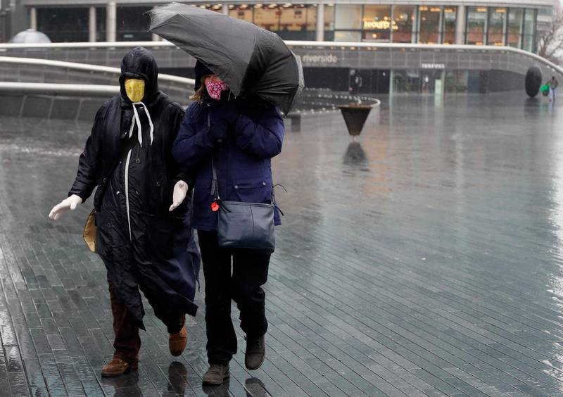 Pedestrians brave the rainy and windy weather in London. AP Photo