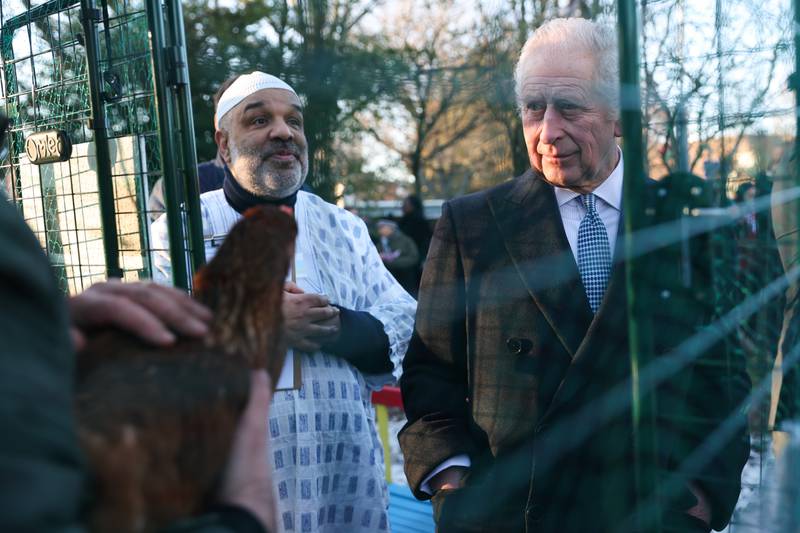 The monarch inspects a chicken during a tour of a community kitchen in Harrow, Greater London. Getty