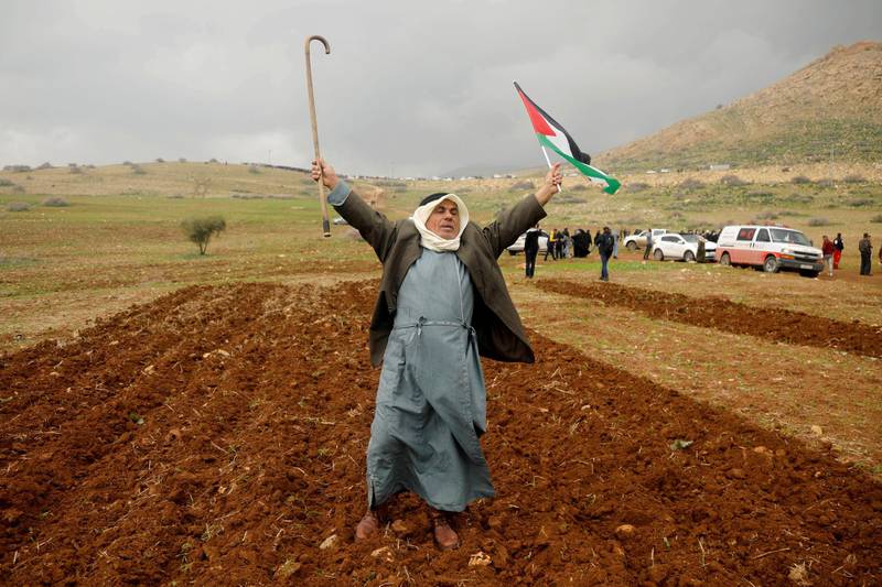 A demonstrator holds up a cane and a Palestinian flag in Jordan Valley in the Israeli-occupied West Bank January 29, 2020. Reuters
